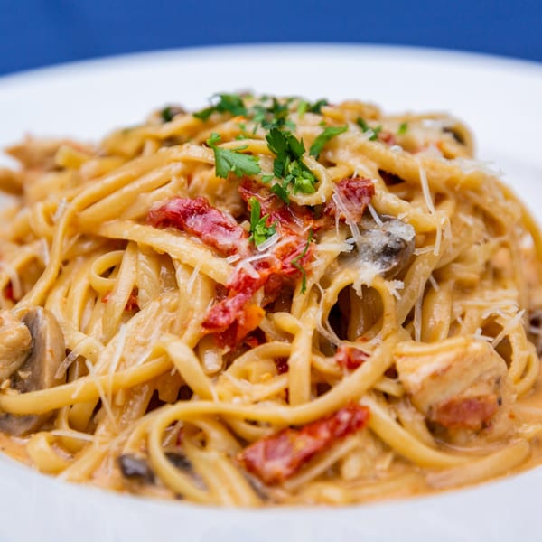 Creamy Faz Restaurants & Catering pasta with sun-dried tomatoes, mushrooms, chicken, and parsley.