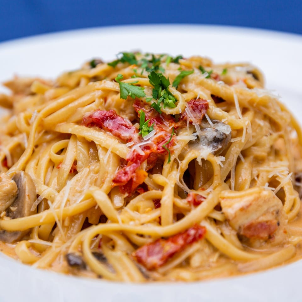Creamy Faz Restaurants & Catering pasta with sun-dried tomatoes, mushrooms, chicken, and parsley.