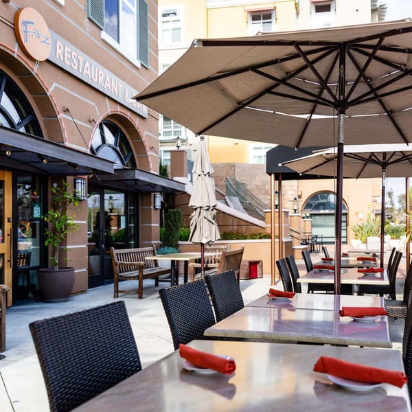 Outdoor patio dining area at Faz Restaurants & Catering with tables, chairs, and umbrellas.