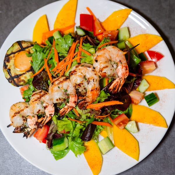 Grilled shrimp and zucchini with a fresh salad of greens, mango, cucumber, and carrots.